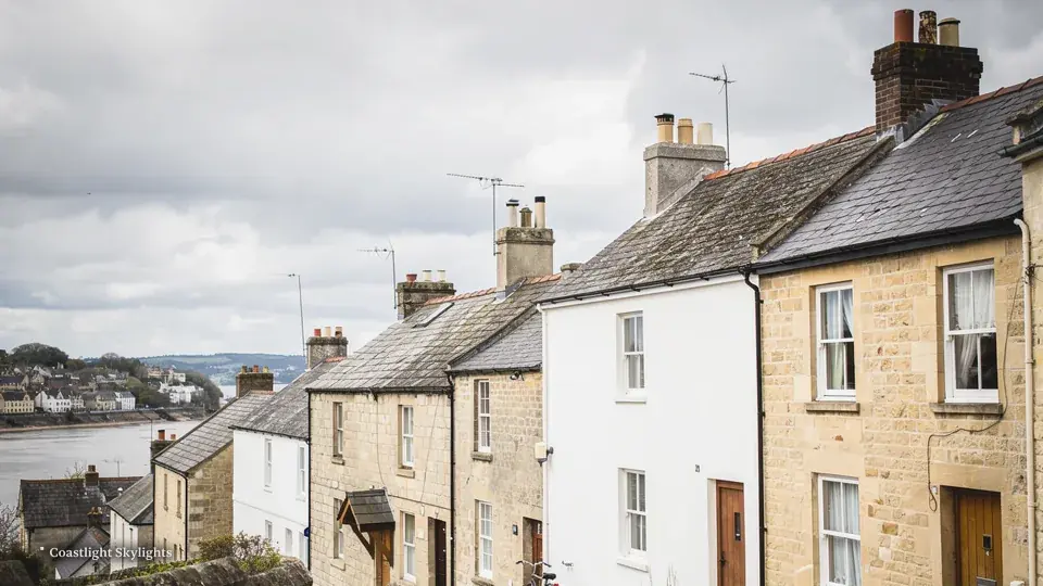 Row of stone terraced houses on a hillside above a stretch of water
