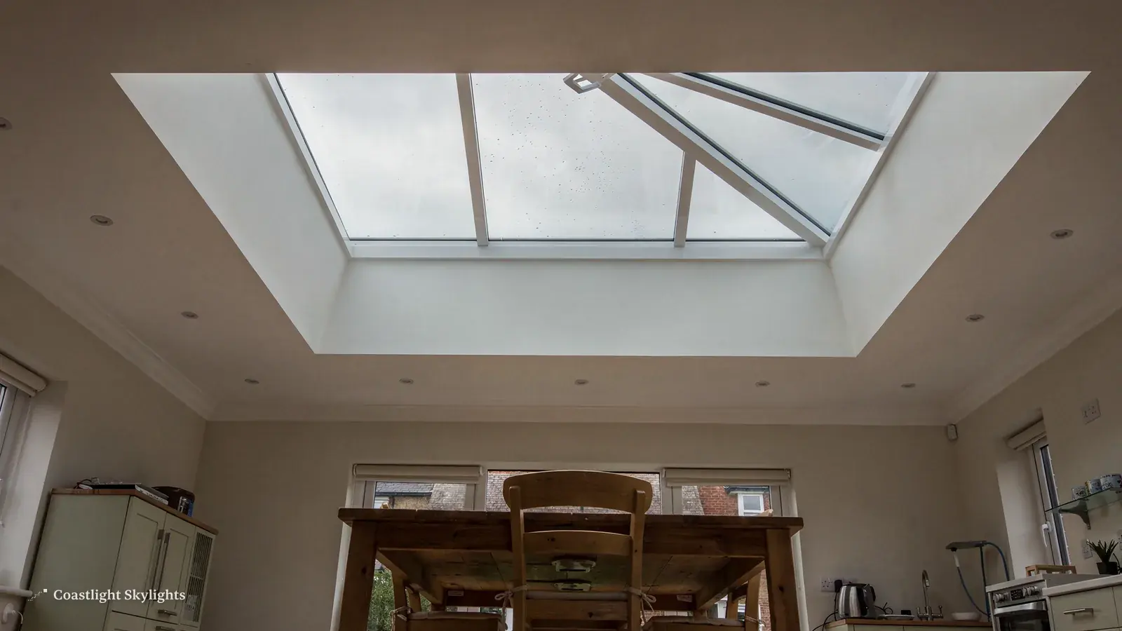 Large glazed rooflight above a wooden dining table in a bright room