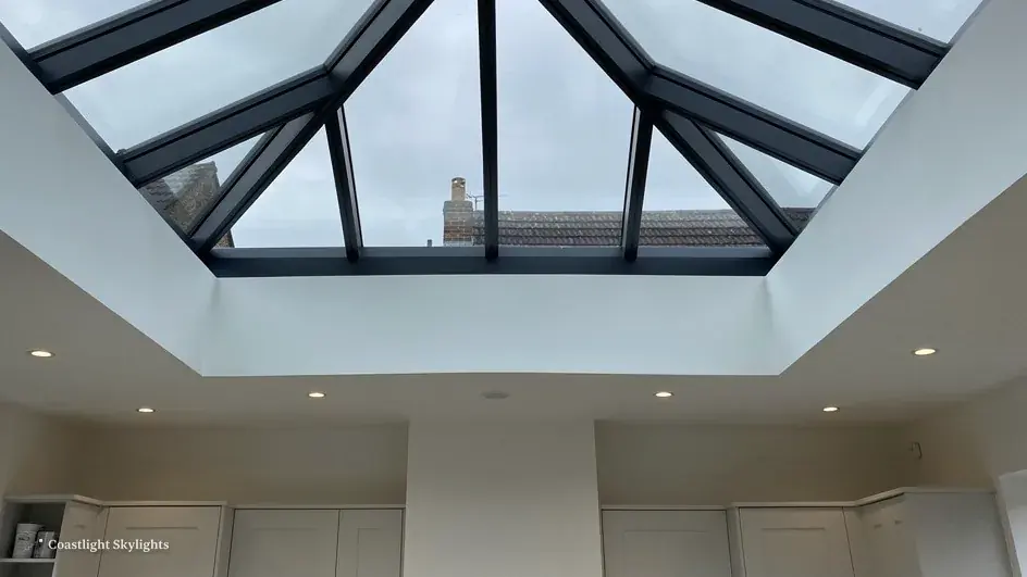 Glazed roof lantern with dark bars seen from below in a white room