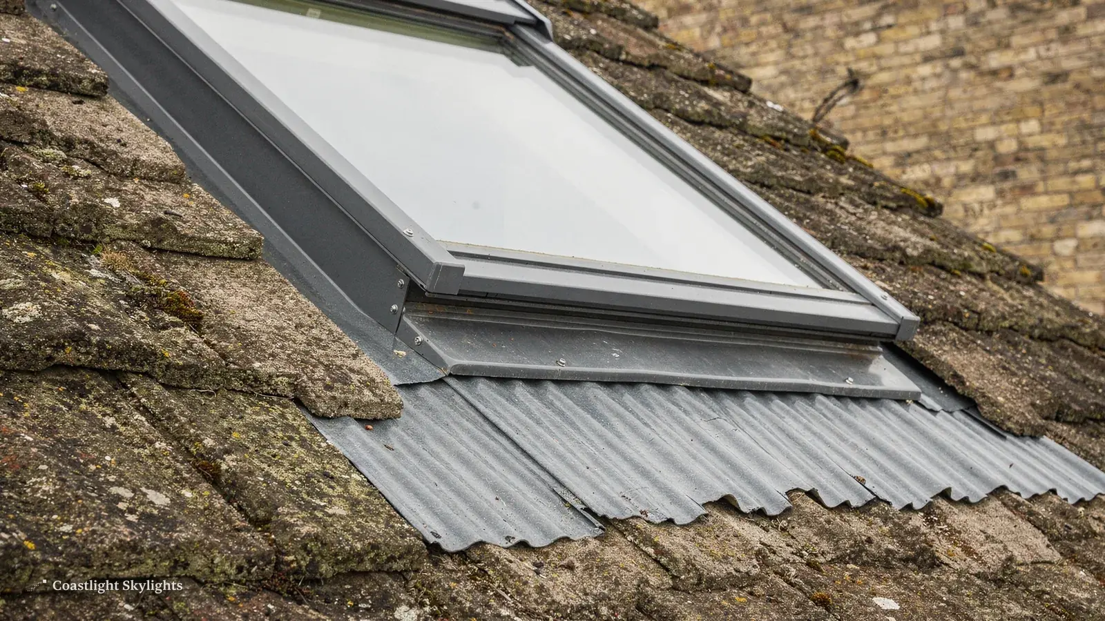 Roof window with metal flashing set into a mossy tiled roof, close view