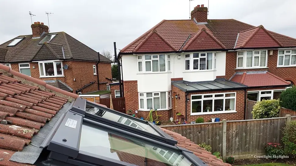Roof window set into a tiled slope beside a row of red and white houses