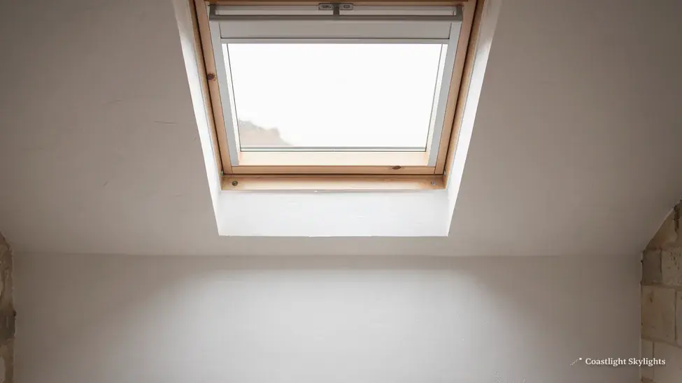 Roof window in a sloping ceiling seen from below with grey walls