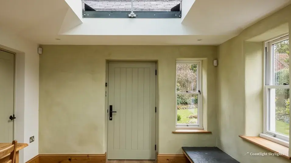 Hallway with a pale green door, white windows and a rooflight in the ceiling