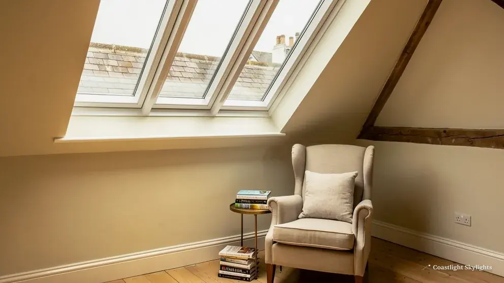 Loft room with an armchair beneath roof windows in the sloping ceiling