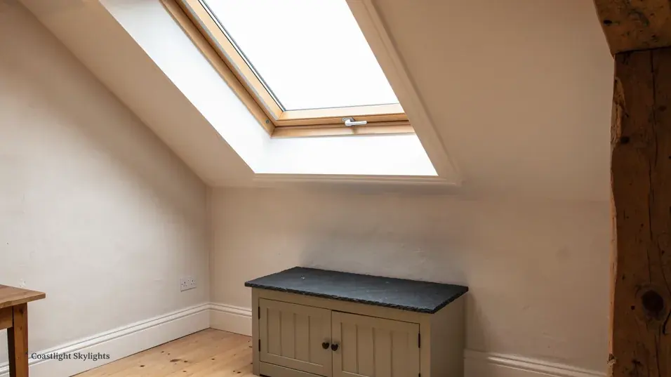 Loft room with a roof window in the sloping ceiling above a cabinet