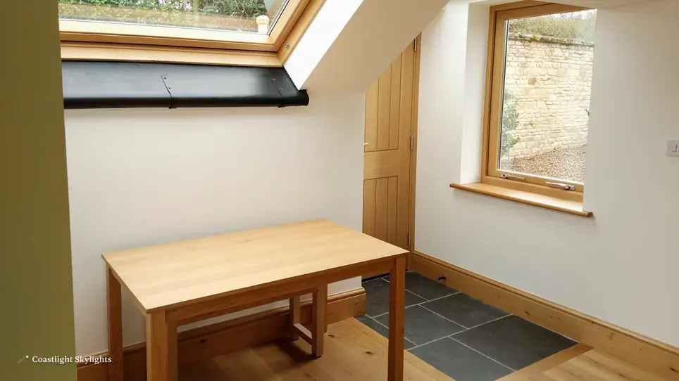 Room with a wooden desk and a roof window high in the sloping ceiling