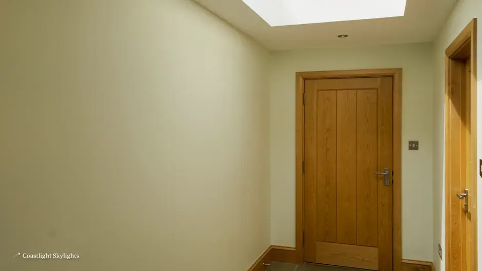 Plain hallway with a pale wall and an oak door