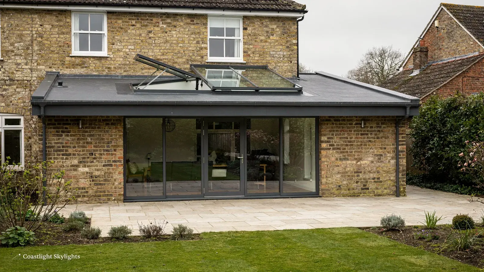 Brick rear extension with a grey flat roof and wide glazed doors onto a terrace