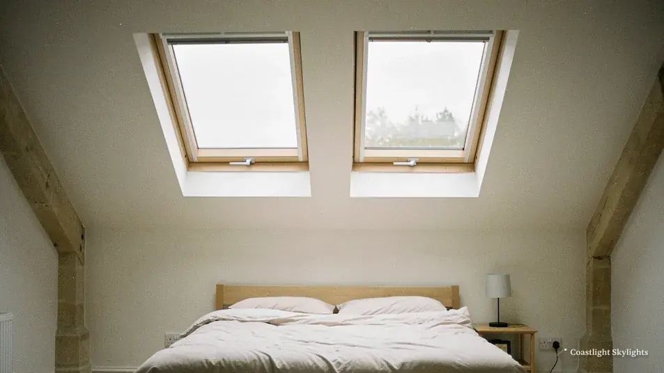 Pair of roof windows above a bed in a loft room with exposed timber beams