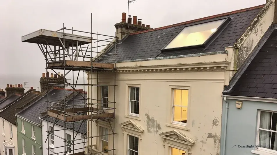 Scaffold against a tall rendered terrace with a roof window set into the pitched roof