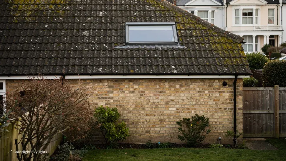 Roof window fitted in the tiled roof of a semi-detached house, seen from the garden