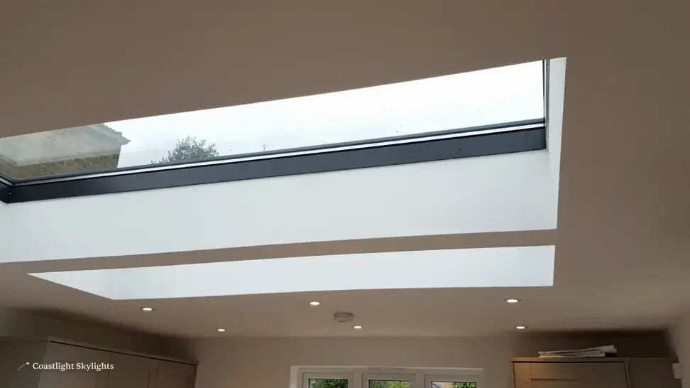 Wide flat rooflight seen from below in a dark ceiling with a clean reveal