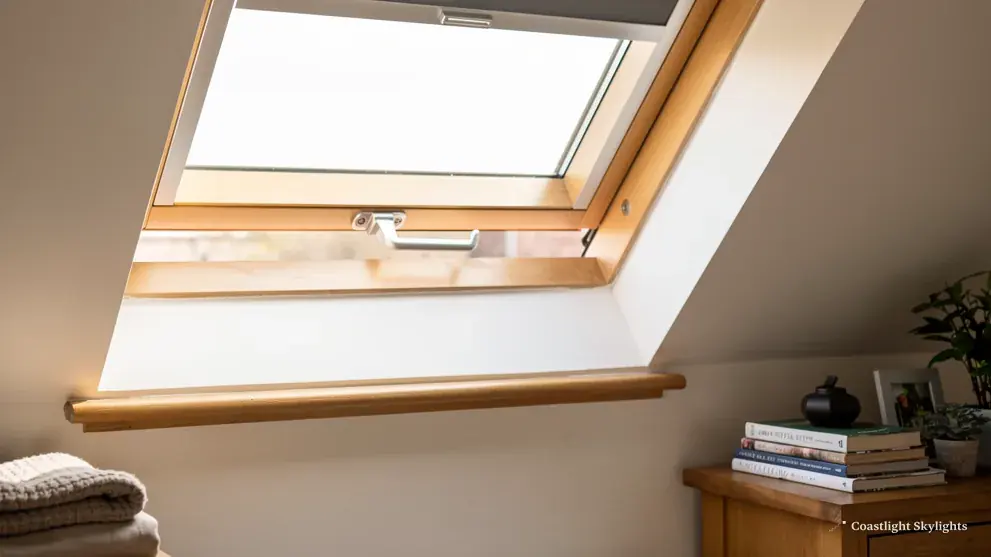 Roof window seen from inside a bright loft room with a wide white sill