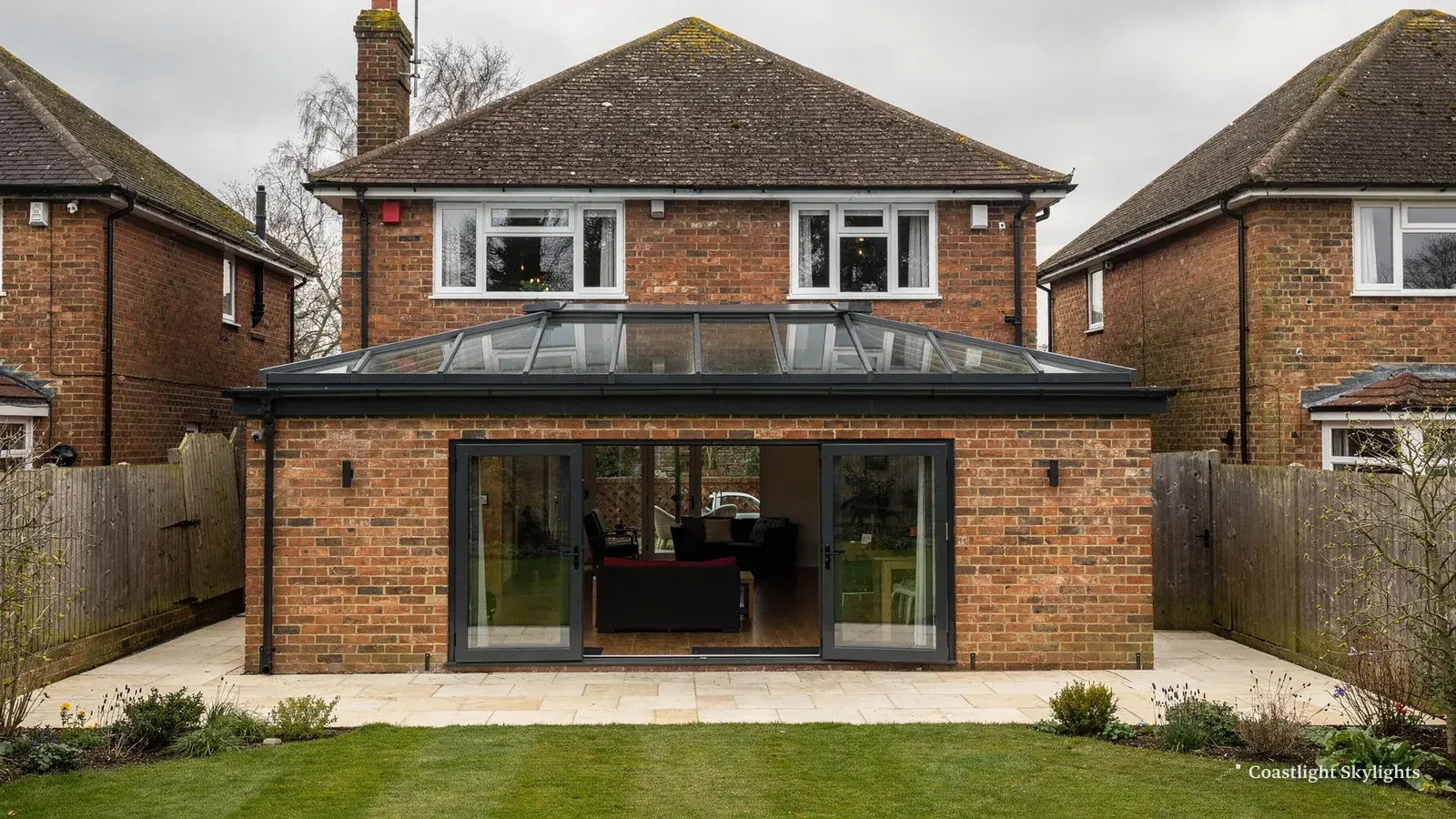 Rear of a brick house with a flat roof extension and glazed doors onto the lawn