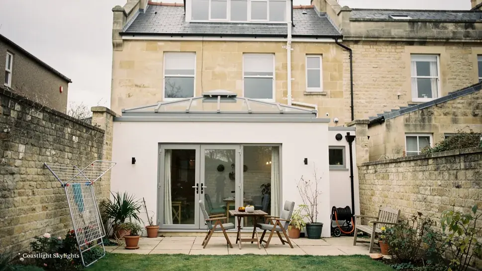 Rear of a rendered house with glazed doors, a patio and a garden