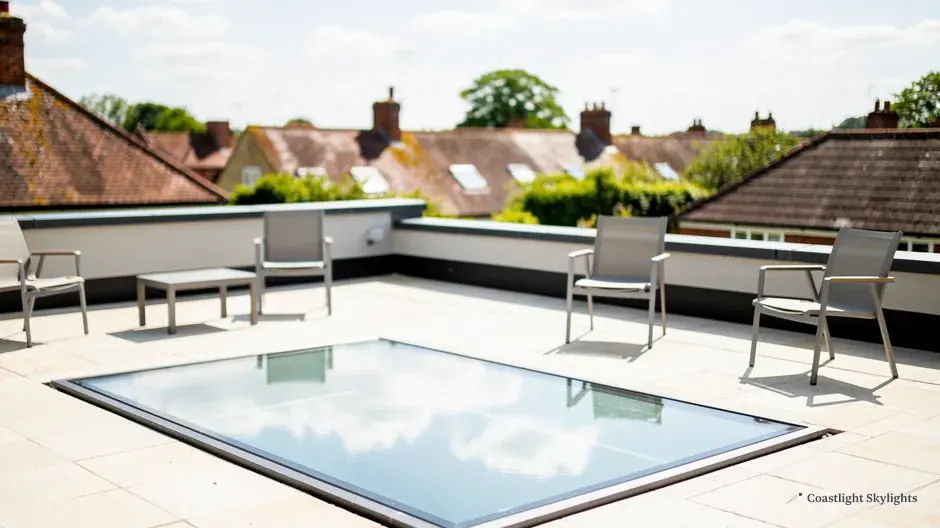 Glass walk-on rooflight set into a roof terrace with chairs beside it