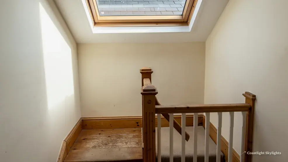 Stairwell landing with a timber newel post and a roof window in the sloping ceiling