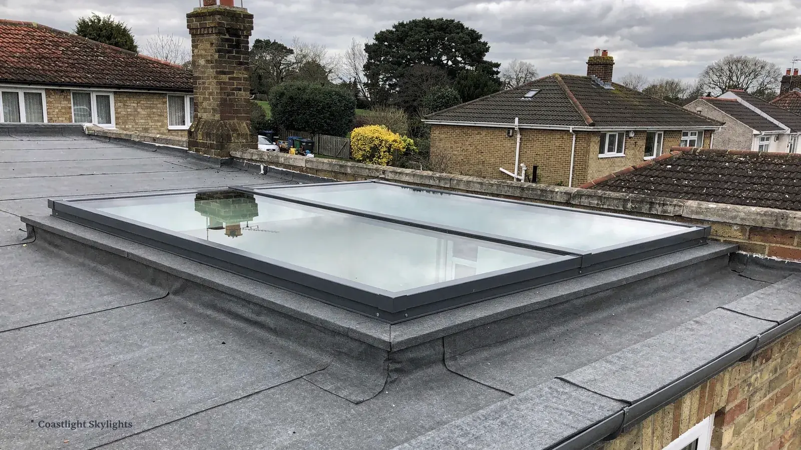 Flat rooflight on a grey flat roof with terraced houses beyond