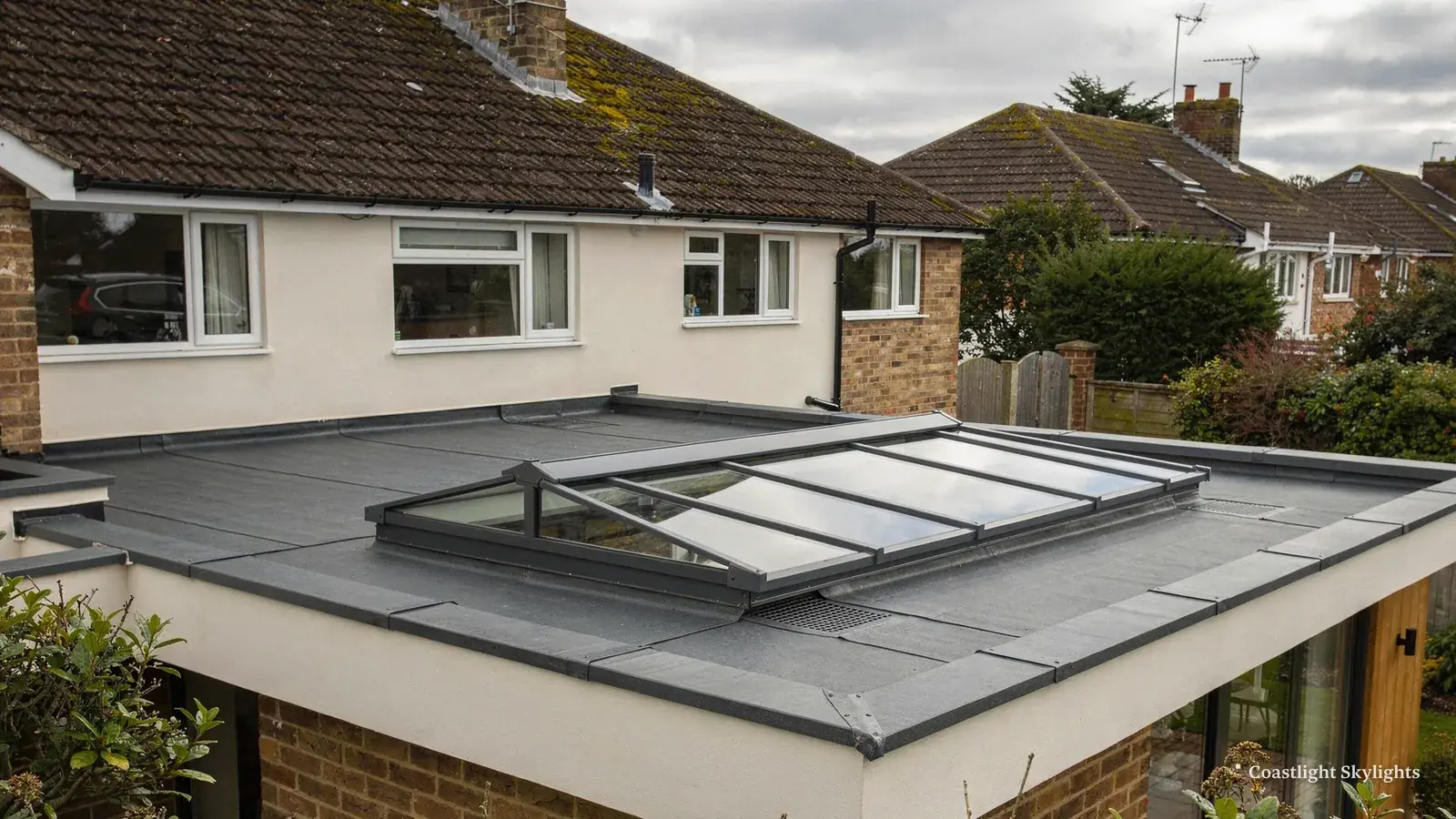Large glazed rooflight on a grey flat roof with terraced houses behind