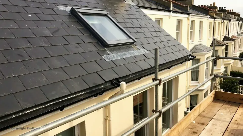 Roof window set into a slate roof on a terraced house with a balcony beside it