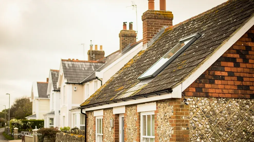 Flint cottage on a village street with a small roof window in its tiled roof