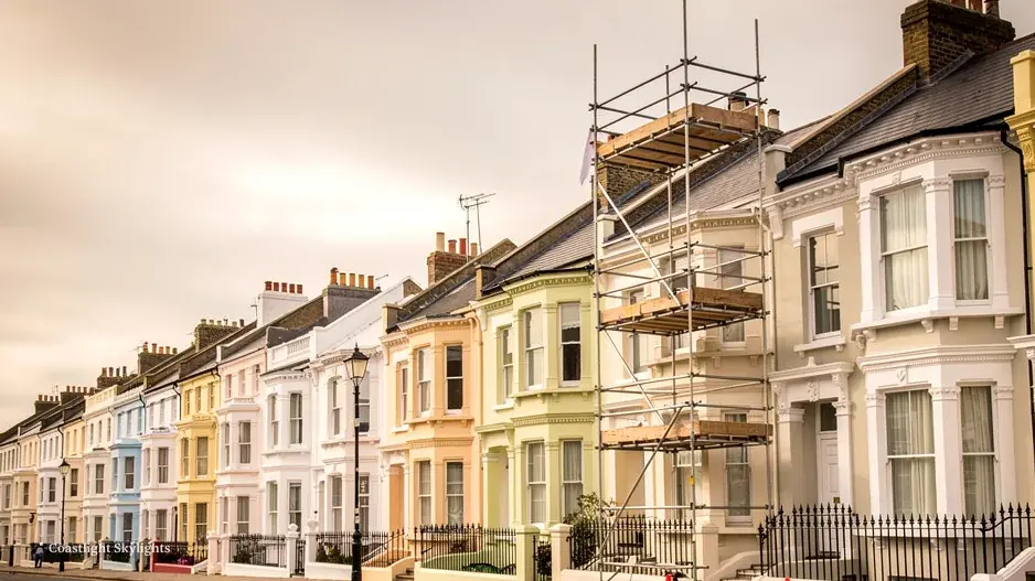 Scaffold tower beside a terraced house with cones marking a cleared parking bay