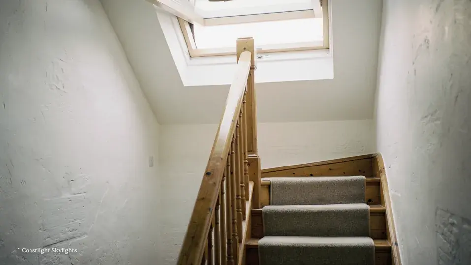 Staircase rising to a landing with a roof window above in the sloping ceiling