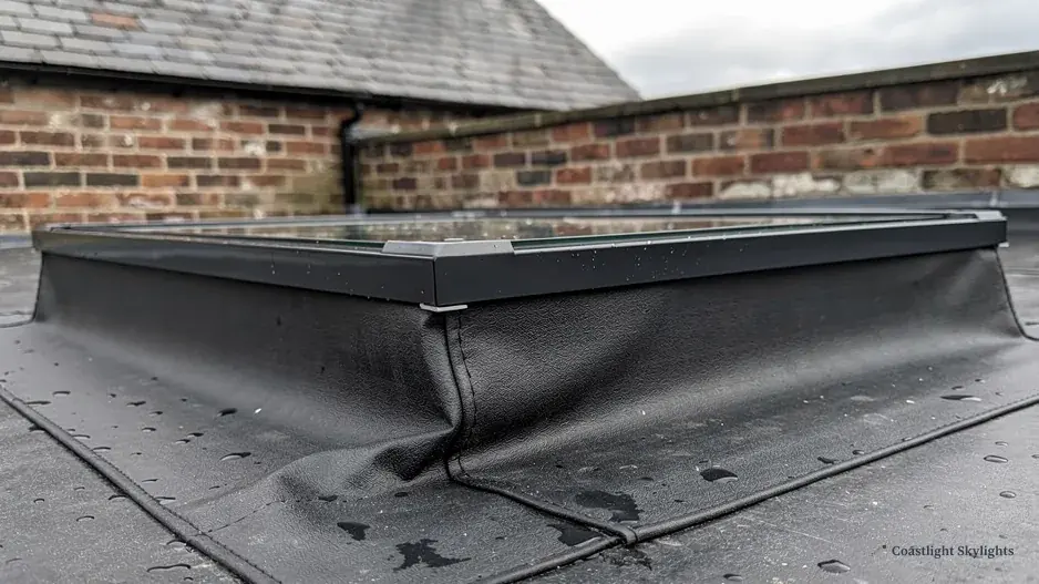 Wrinkled roof membrane around a flat rooflight kerb with debris on the roof