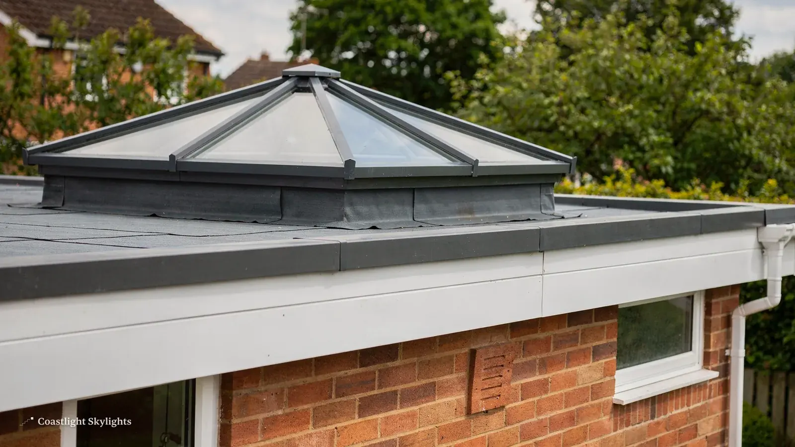 Glass pyramid roof lantern on a grey flat roof extension with a lawn beside it