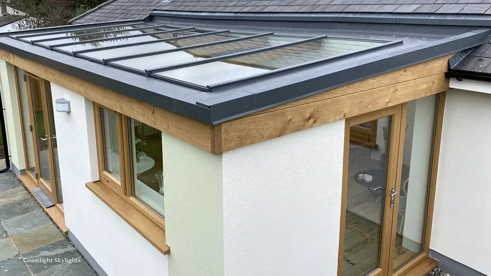 Flat roof extension with a grey fascia, oak framed windows and doors, and a rooflight