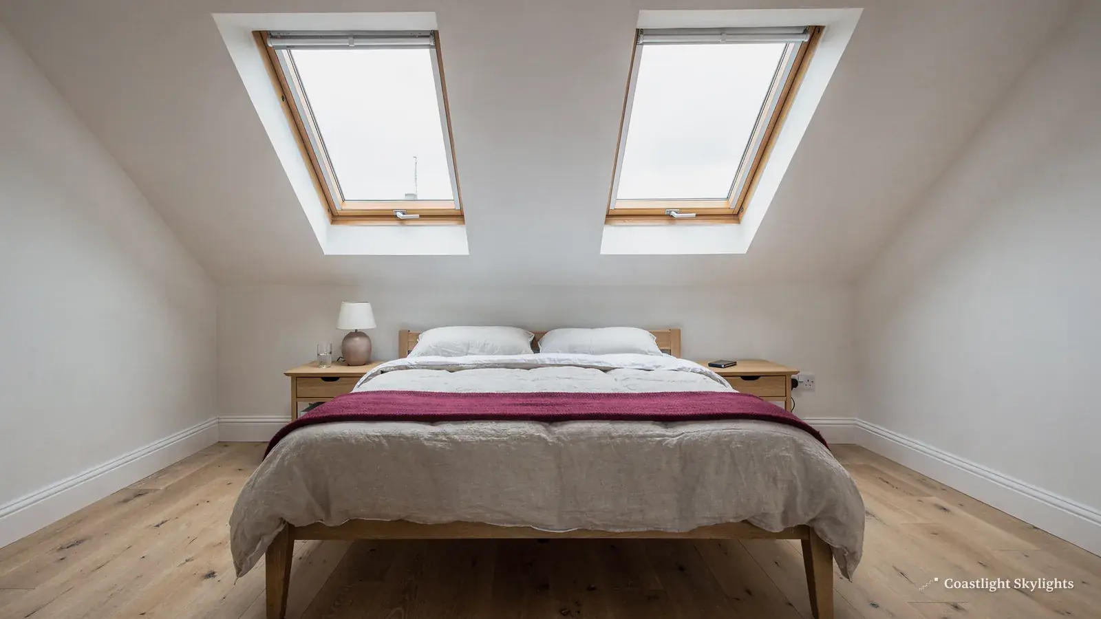 Two roof windows above a bed in a white loft bedroom