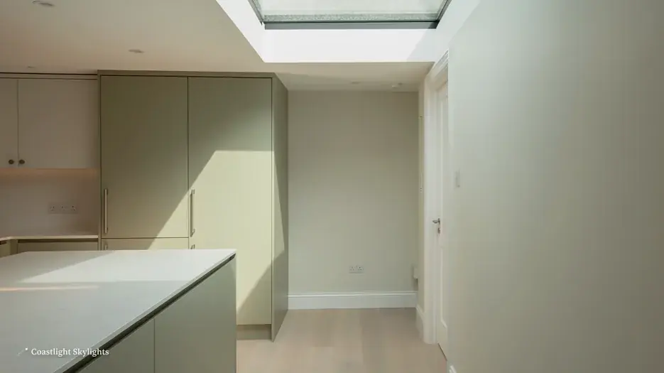 Looking up at a flat rooflight in a pale ceiling in a sage green room
