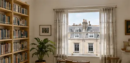 A room with a tall sash window looking across to a terrace opposite
